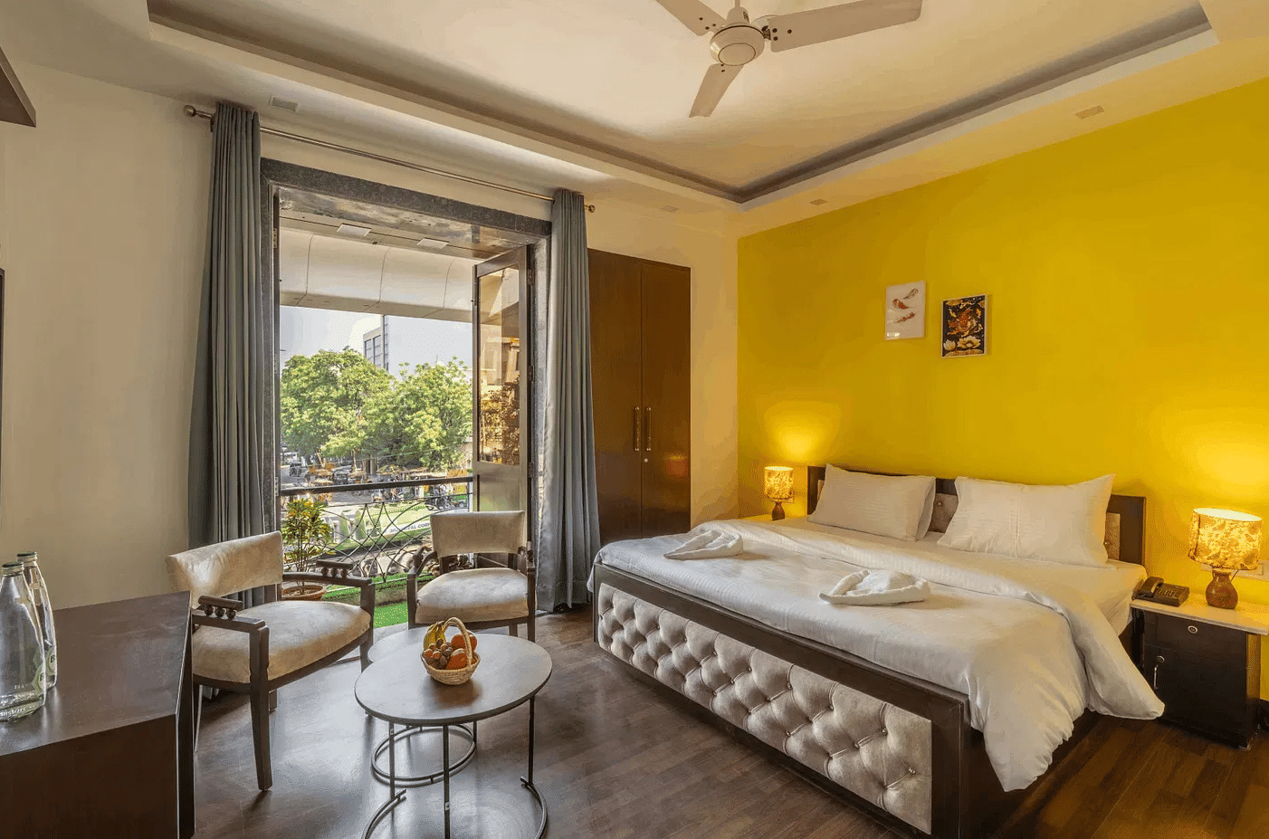 A hotel room with twin beds, yellow accents, and a view of greenery through the window - Lime Boutique Bed & Breakfast | Nehru Place Metro